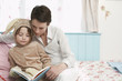 Mother and daughter 5-6 in bedroom reading book, girl in bunny costume