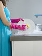 Photo: Woman wearing dress and rubber gloves, washing dishes, side view, mid section Woman wearing dress and rubber gloves, washing dishes, side view, mid section