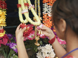 Photo: Young woman looking at artificial flowers necklaces, back view, selective focus Young woman looking at artificial flowers necklaces, back view, selective focus
