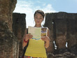Photo: Young woman reading guide book, ancient ruins in background Young woman reading guide book, ancient ruins in background