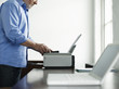 Middle-aged man using printer, side view, mid section