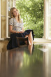 Young woman sitting on window sill in living room