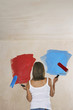 Photo: Woman facing wall painted on ble and red, holding with paint rollers, back view Woman facing wall painted on ble and red, holding with paint rollers, back view