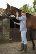 Woman with horse outside stable, portrait