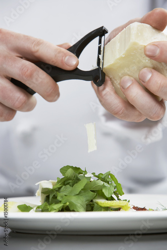 Foto: Male chef grating cheese over salad, mid section Male chef grating cheese over salad, mid section