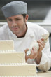 Male chef icing wedding cake in kitchen