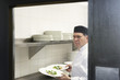 Man chef holding plates of food in kitchen