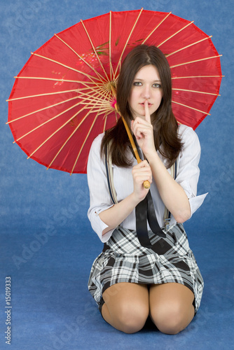 Photo: Girl with a red umbrella on blue background Girl with a red umbrella on blue background