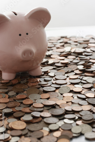 Photo: Piggy bank and vast amount of coins Piggy bank and vast amount of coins