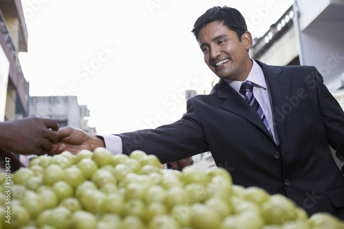Photo: business man paying fruit merchant low angle view business man paying fruit merchant low angle view