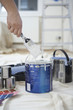 Man dipping paint brush into can, close up of hand