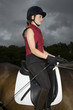 Female horseback rider sitting on brown horse