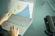 Businesswoman's hands with laptop showing bar chart
