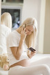 Pregnant woman using mobile phone on bed