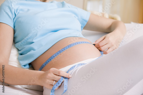 Photo: Pregnant woman measuring stomach on bed Pregnant woman measuring stomach on bed