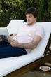 Young man on chaise lounge reading