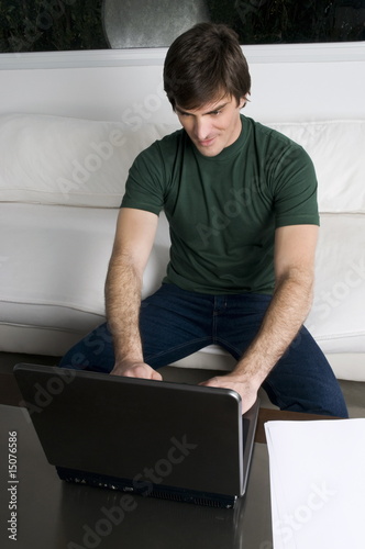 Photo: Young man with laptop computer on couch Young man with laptop computer on couch