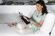 Young woman on couch reading magazine