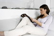 Young woman on couch reading magazine
