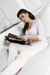 Young woman on couch reading magazine