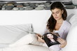 Young woman on couch reading magazine