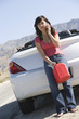 Female driver on mobile with petrol canister at roadside