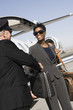 Mid-adult businesswoman giving suitcase to chauffeur in front of airplane