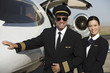 Portrait of mid-adult airline pilot and flight attendant in front of  airplane.
