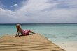 A girl sits on a dock overlooking the Caribbean ocean