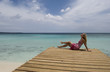 A woman sits on a dock looking over the Caribbean