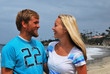 A cute couple smiling at each other on the beach.