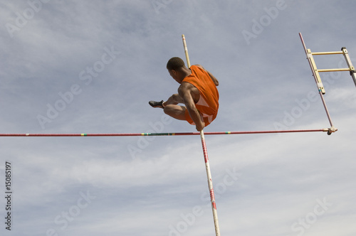 Photo: Pole vaulted in mid-air, low angle view Pole vaulted in mid-air, low angle view