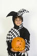 Portrait of boy 7-9 wearing jester costume, with jack-o-lantern