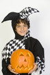 Portrait of boy 7-9 wearing jester costume, with jack-o-lantern