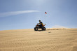 young man riding atv over sand dune