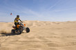 young man riding atv over sand dune