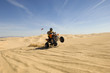 young man riding atv over sand dune