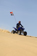 young man riding atv over sand dune