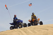 young men riding atvs over sand dunes