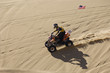 Young Man Riding ATV Over Sand Dune