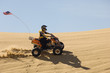 young man riding atv over sand dune