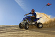 young man riding atv over sand dune