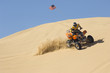 young man riding atv over sand dune