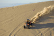 young man riding atv over sand dune
