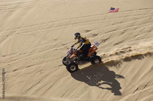 Photo: Young Man Riding ATV Over Sand Dune Young Man Riding ATV Over Sand Dune