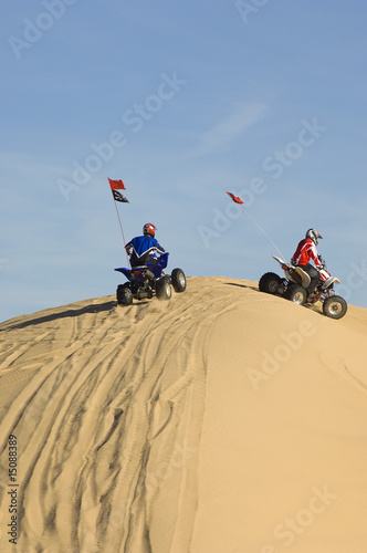 Photo: young men riding atvs over sand dunes young men riding atvs over sand dunes