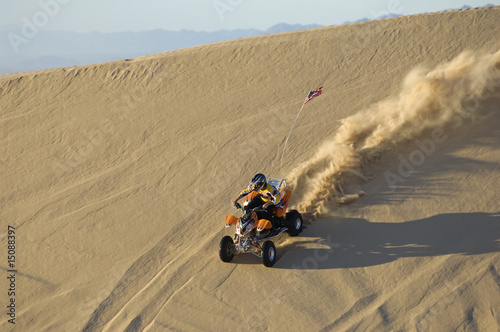 Photo: young man riding atv over sand dune young man riding atv over sand dune