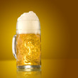 Foto: Glass of beer close-up with froth over yellow background Glass of beer close-up with froth over yellow background