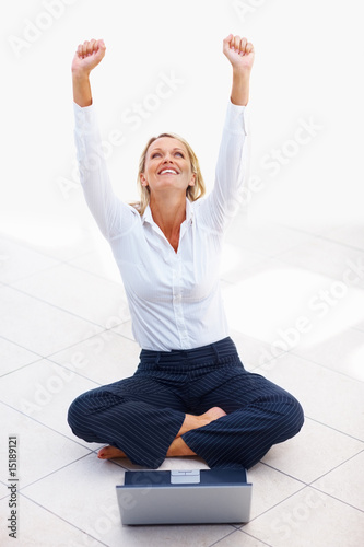 Achievement: Happy young business woman using a laptop on white
