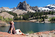 A man enjoying the sun next to a mountain lake.